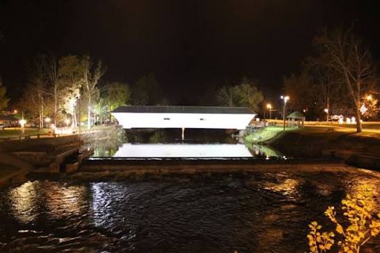 Elizabethton Covered Bridge lit at night reflecting on the river