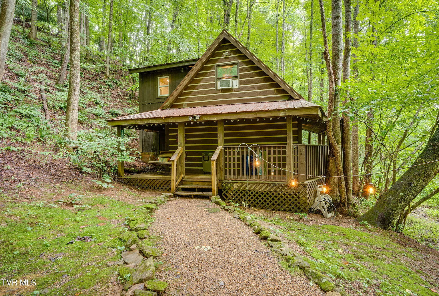 Creek Cabin with porch swing and stone path through the timber
